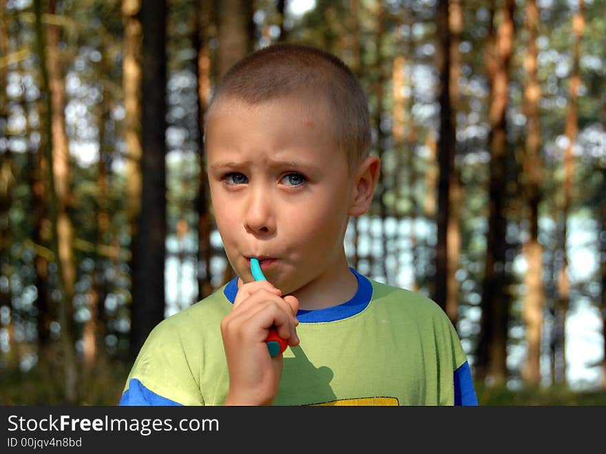 Nearly 5 years young boy is brushing his teeth in forest