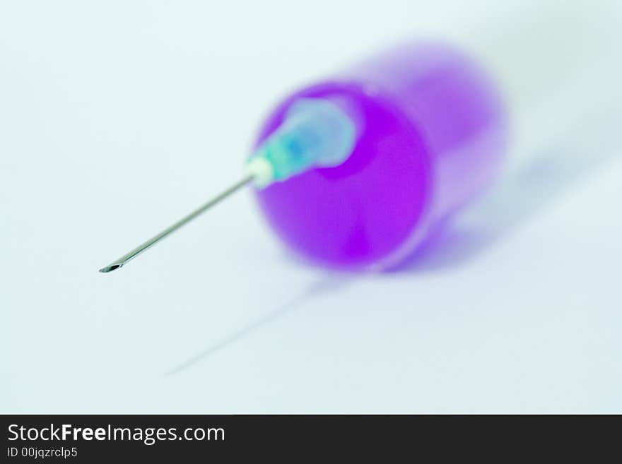 Disposable syringe with needle on it filled with violet liquid against the white background. Disposable syringe with needle on it filled with violet liquid against the white background