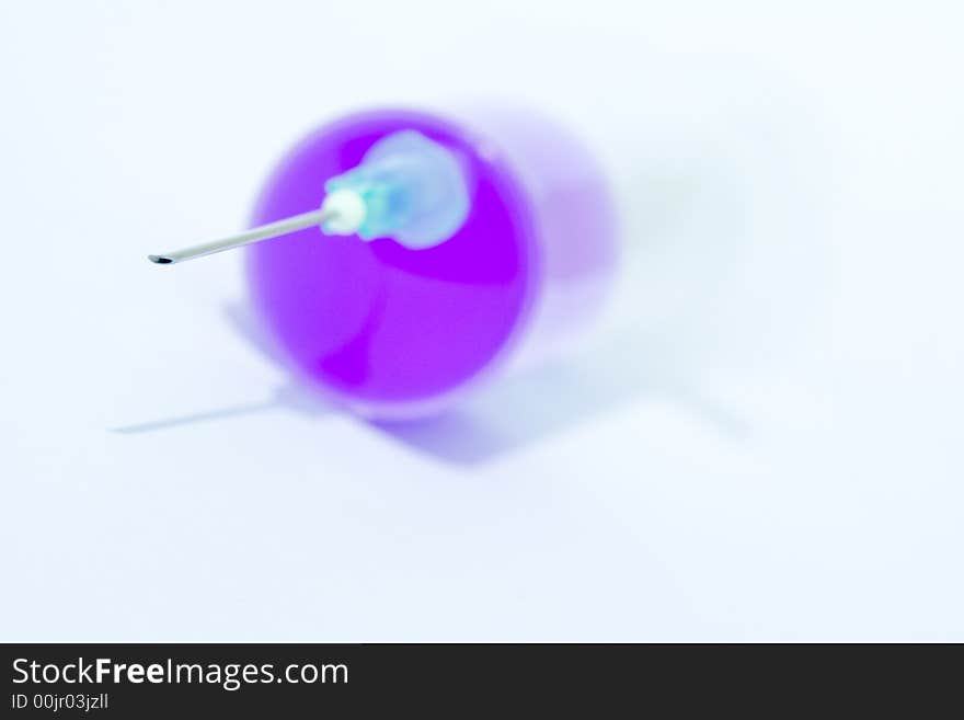 Disposable syringe with needle on it filled with violet liquid against the white background. Disposable syringe with needle on it filled with violet liquid against the white background