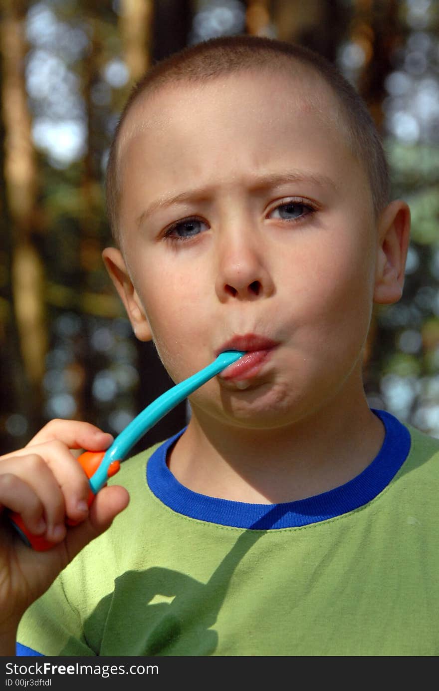 Nearly 5 years young boy is brushing his teeth in forest