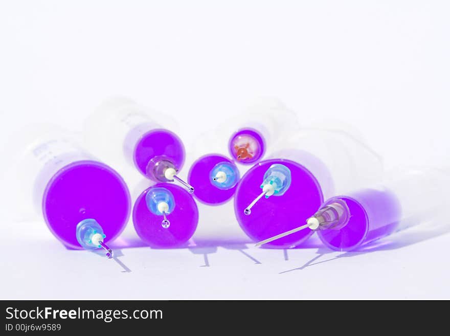 Six different size disposable syringes filled with purple fluid with needles against the white background. Six different size disposable syringes filled with purple fluid with needles against the white background