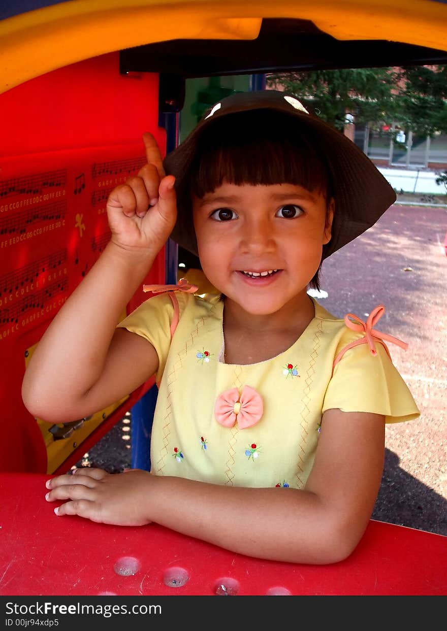 Young pretty girl on the playground. She is pointing her finger up. Young pretty girl on the playground. She is pointing her finger up.