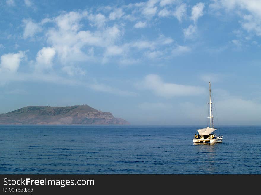 Yacht in the sea on a background of seashore and clouds. Yacht in the sea on a background of seashore and clouds