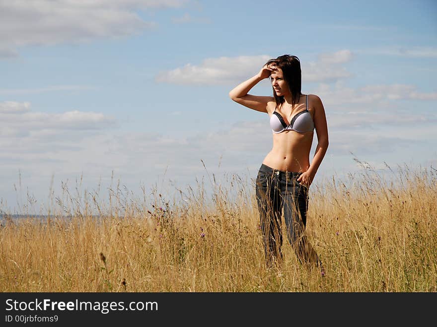 Young teenage girl stands alone in sunmmer landscape. Young teenage girl stands alone in sunmmer landscape.