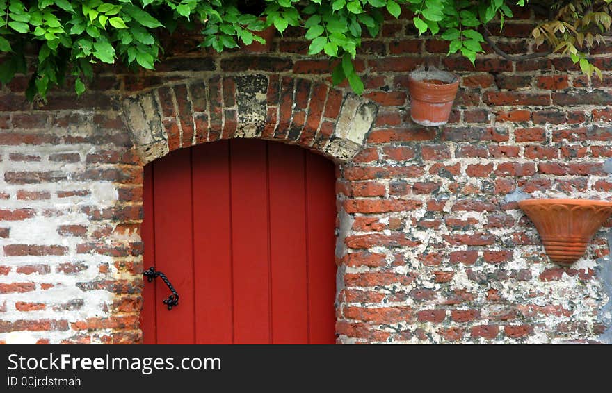 Detail of a old building showing part of a red door and brick wall. Detail of a old building showing part of a red door and brick wall