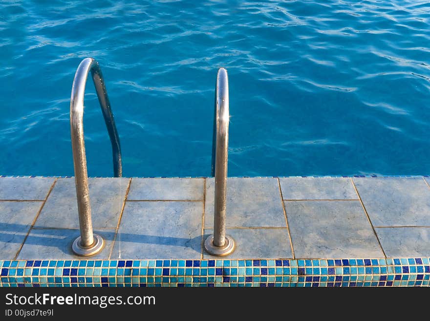 Metal staircase to water in swimming pool. Metal staircase to water in swimming pool