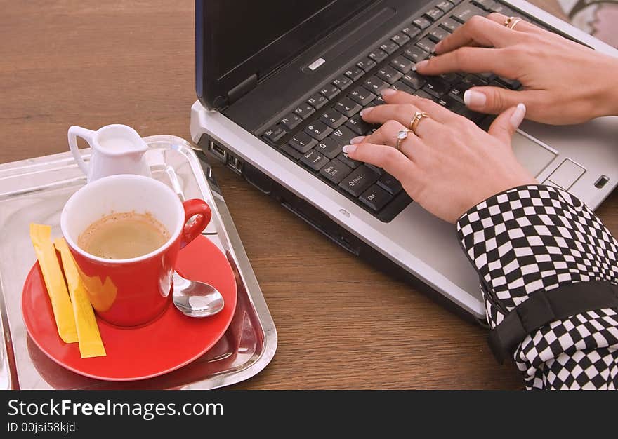 Detail image of woman's hands typing on a laptop at a coffee table. Detail image of woman's hands typing on a laptop at a coffee table.