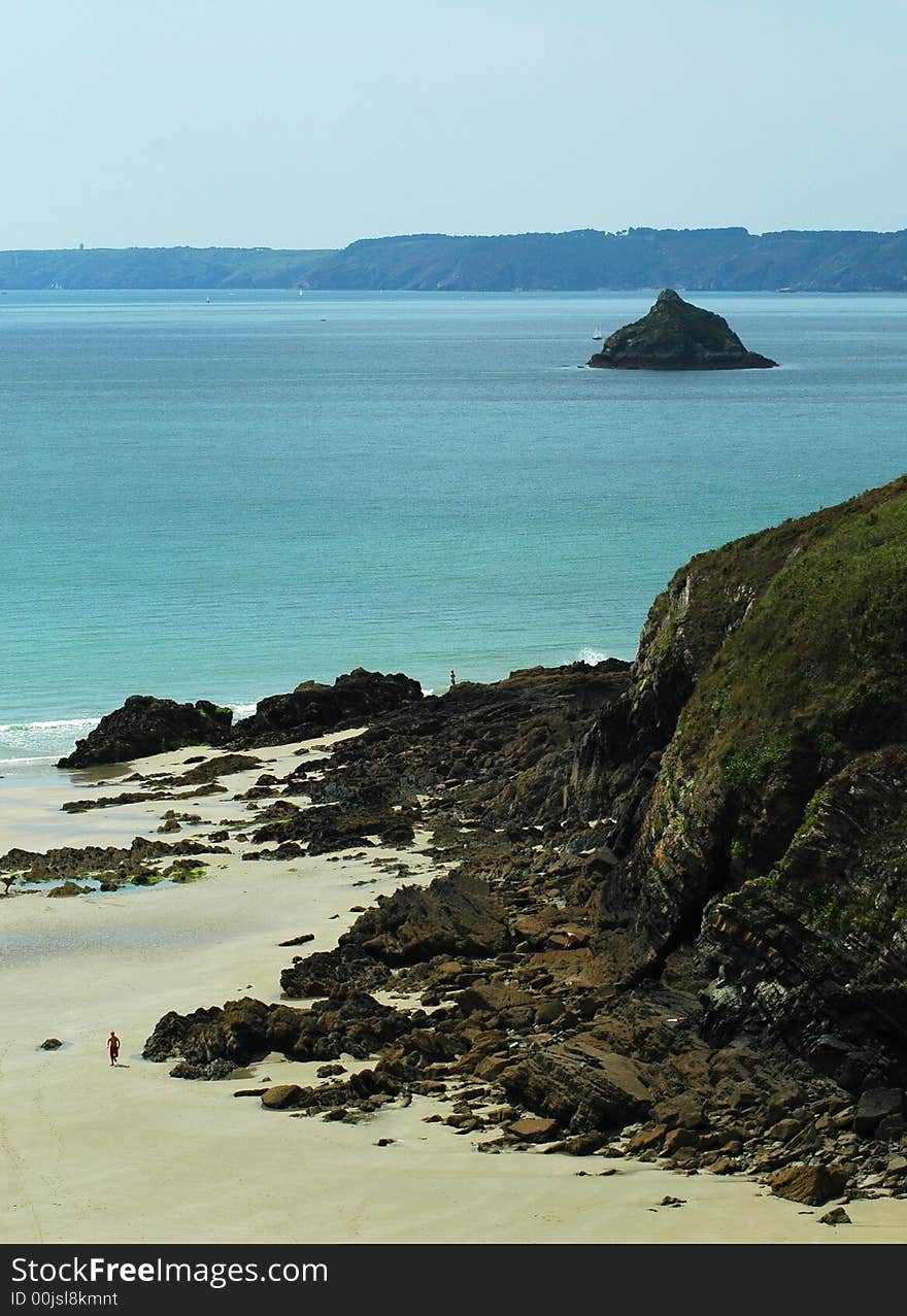 A deserted beach in brittany with a small island in the distance