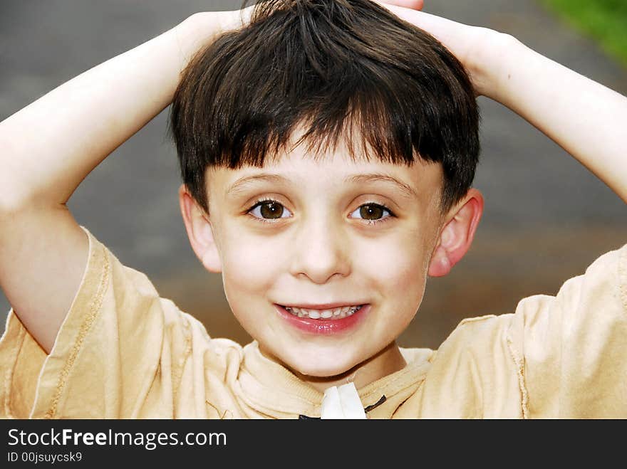 LIttle boy posing with a happy smile on his face and his hands on his head showing his perfect baby teeth. LIttle boy posing with a happy smile on his face and his hands on his head showing his perfect baby teeth