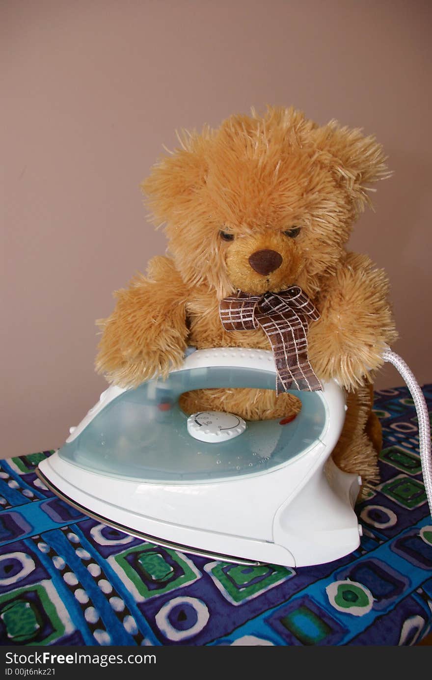 A teddy beard placed on an ironing board, ironing. A teddy beard placed on an ironing board, ironing