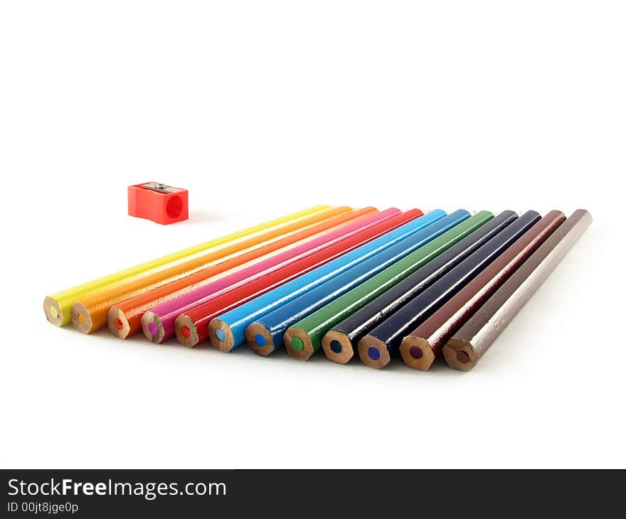 School and office articles: coloured pencils and pencil sharpener on white background