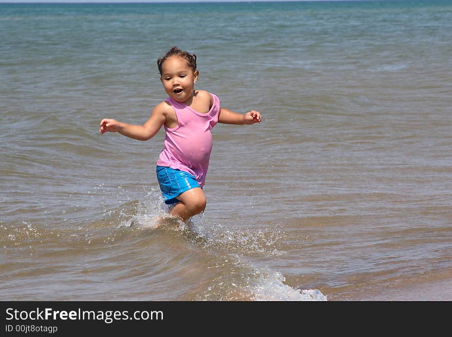 Little toddler girl running in the waves of Lake Michigan