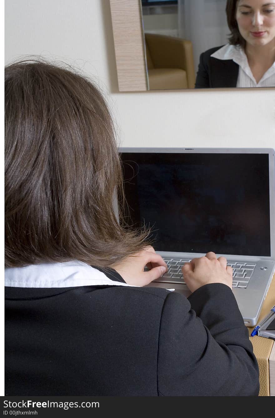 A young attractive businesswoman working on her laptop, focus on her. A young attractive businesswoman working on her laptop, focus on her