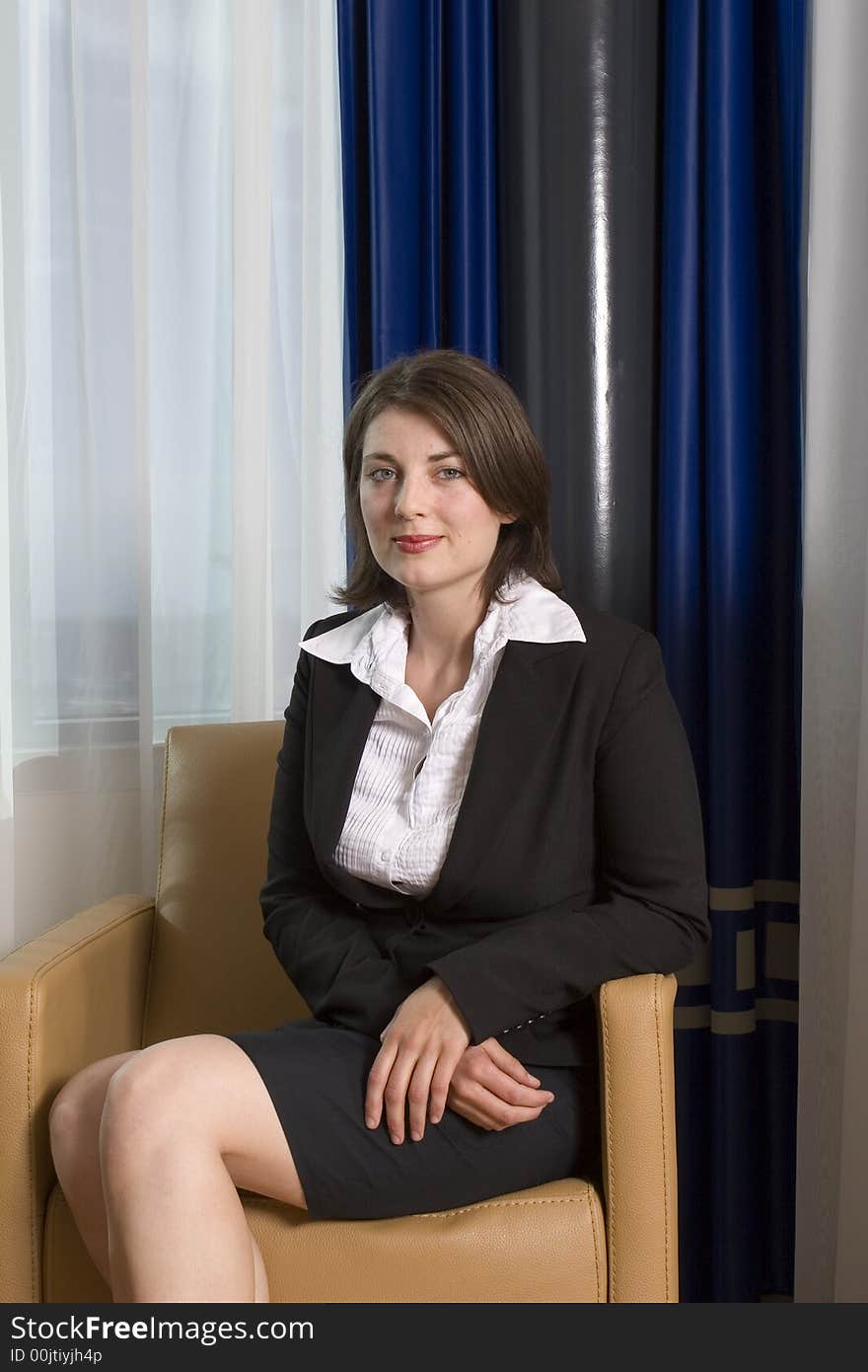 A young attractive businesswoman sitting in a chair looking at camera. A young attractive businesswoman sitting in a chair looking at camera