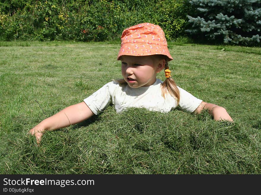 A girl having fun in a heap of just cut grass. A girl having fun in a heap of just cut grass