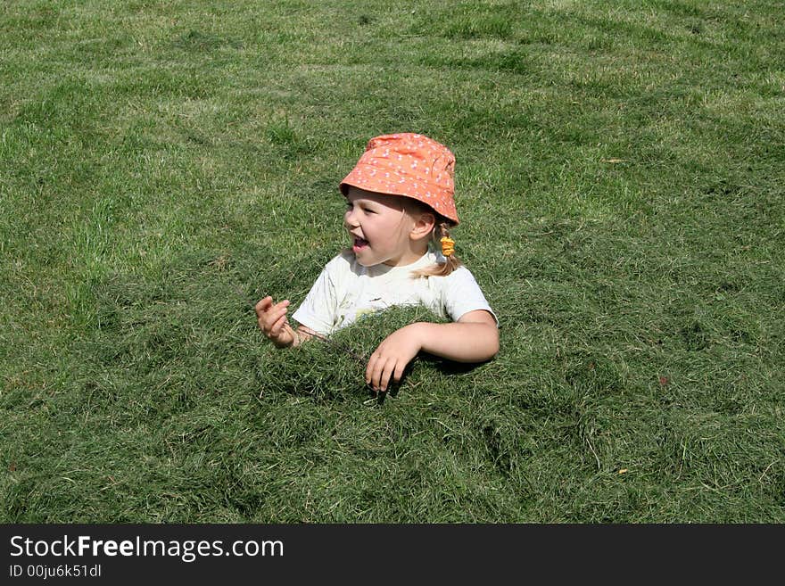 A girl having fun in a heap of just cut grass. A girl having fun in a heap of just cut grass