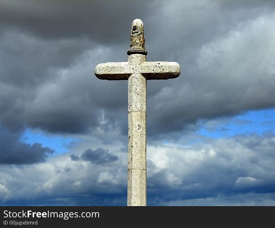 Stone cross with brooding cloudy sky in the background. Stone cross with brooding cloudy sky in the background