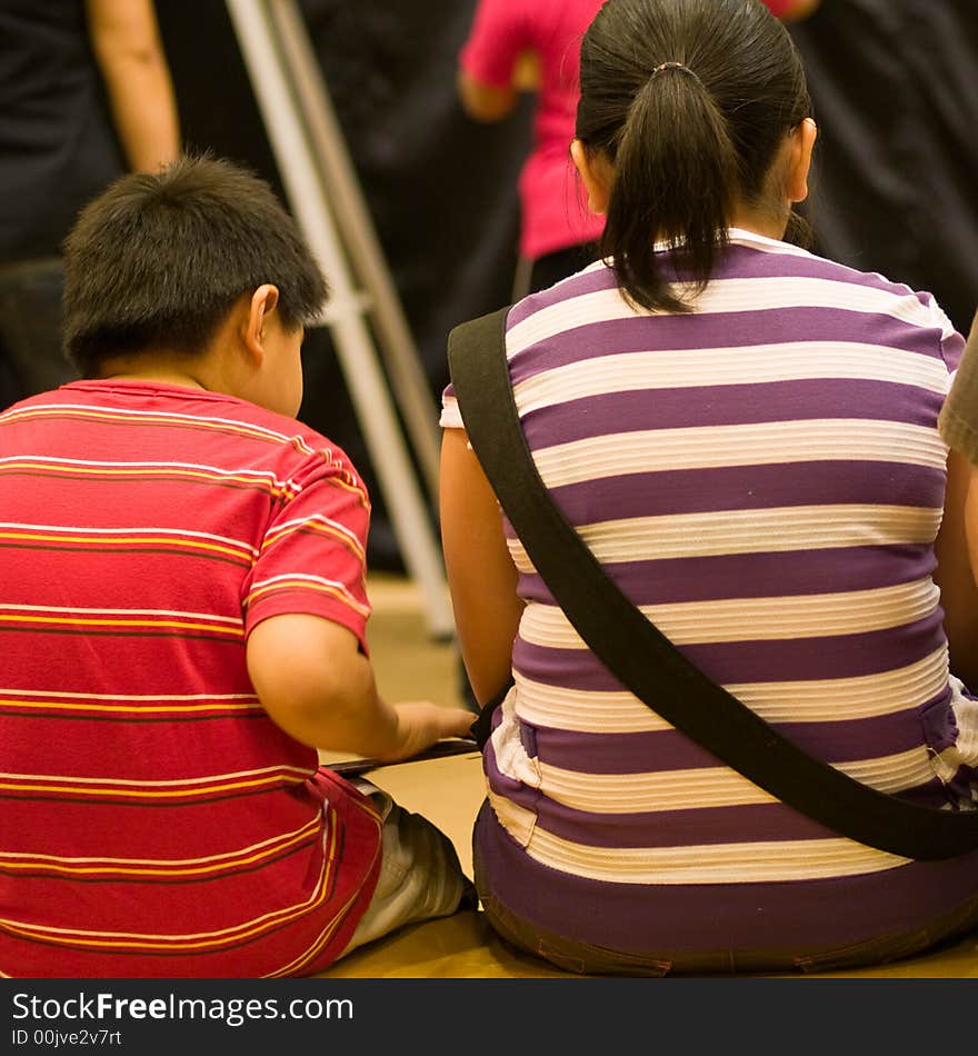 Mother and son similarly dressed in a bookstore's reading area. Mother and son similarly dressed in a bookstore's reading area