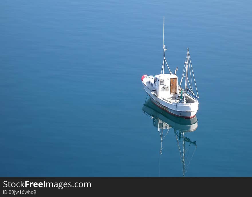 A lone boat floating in a blue sea