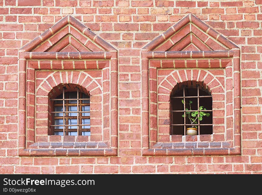 Old windows with bars one of them is opened and there is a green plant. Old windows with bars one of them is opened and there is a green plant