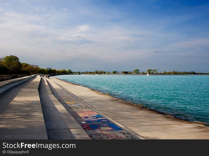 Stepped concrete sidewalk along lake shore with blue water