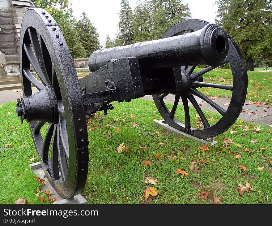 A black cannon guards a monument.