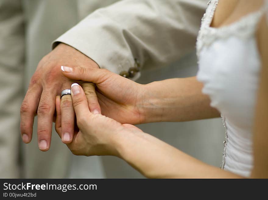 The placement of a tungsten wedding band on the groom. The placement of a tungsten wedding band on the groom