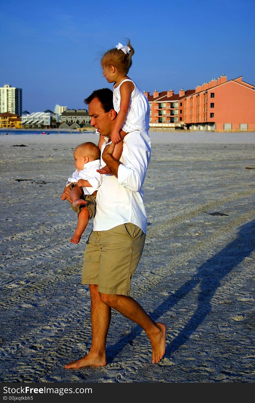 Father walking while holding his daughter and son at the beach. Father walking while holding his daughter and son at the beach