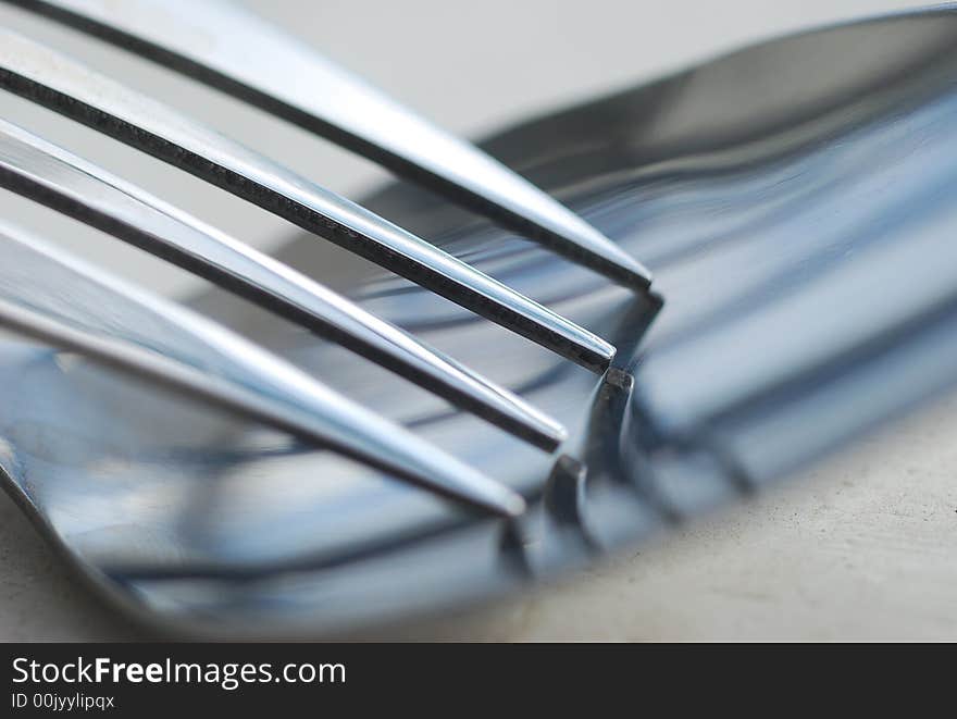 A close-up image of a fork resting in a spoon. A close-up image of a fork resting in a spoon