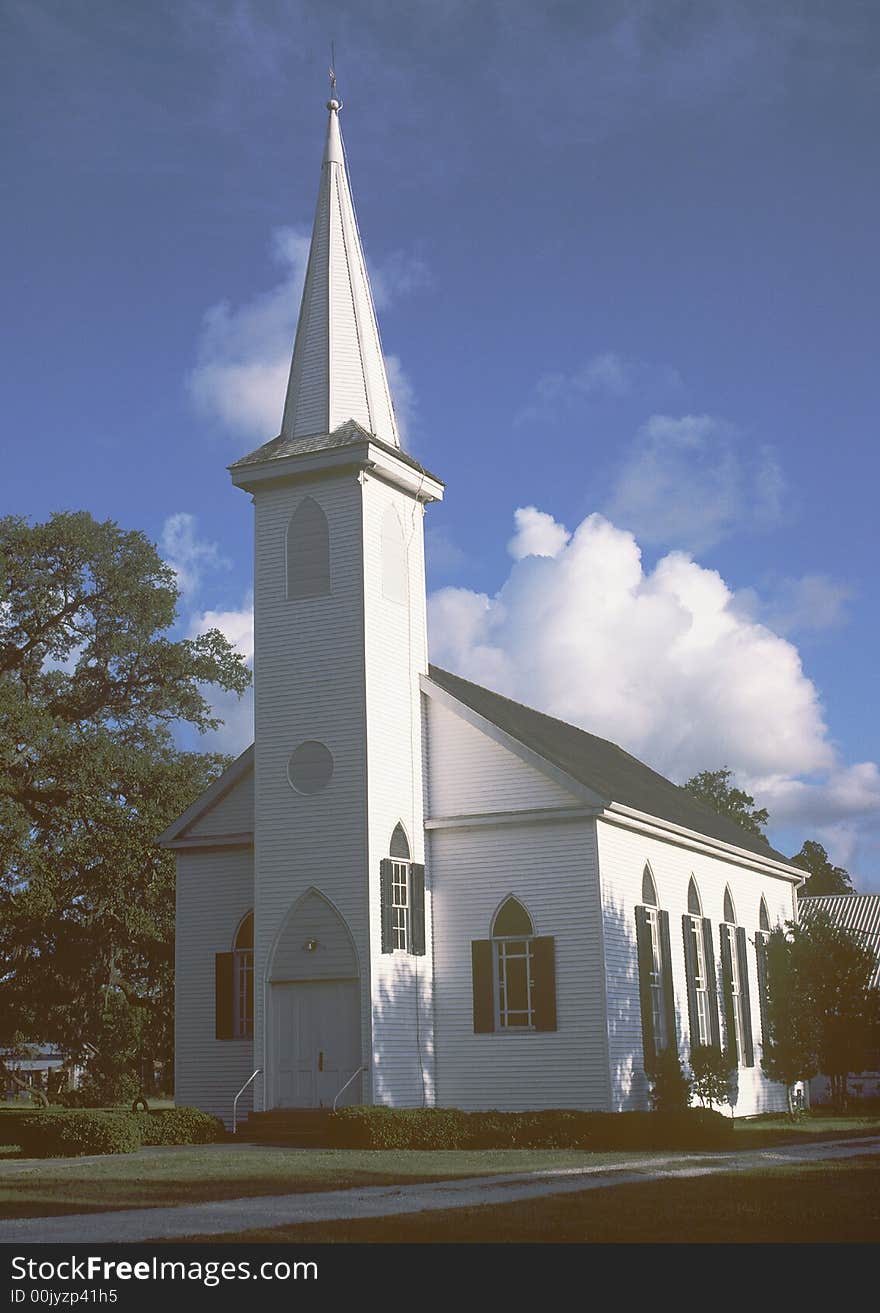 Beautiful picture of a church taken near sundown with shadows and blue sky and billowing clouds