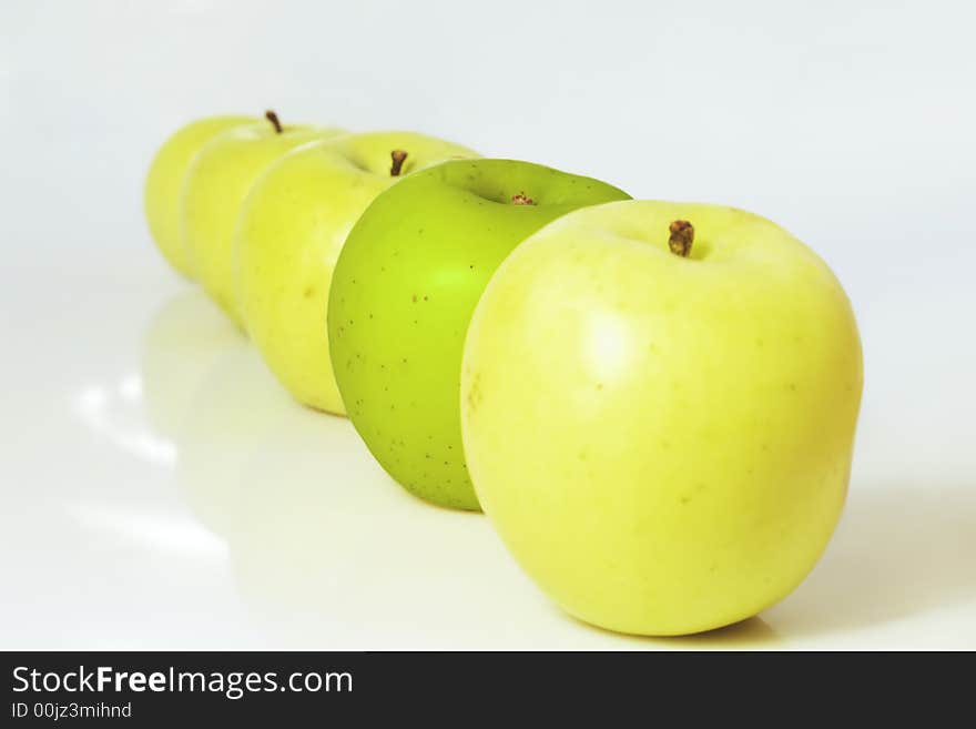 Individuality concept - a group of yellow apples with a green one. Individuality concept - a group of yellow apples with a green one