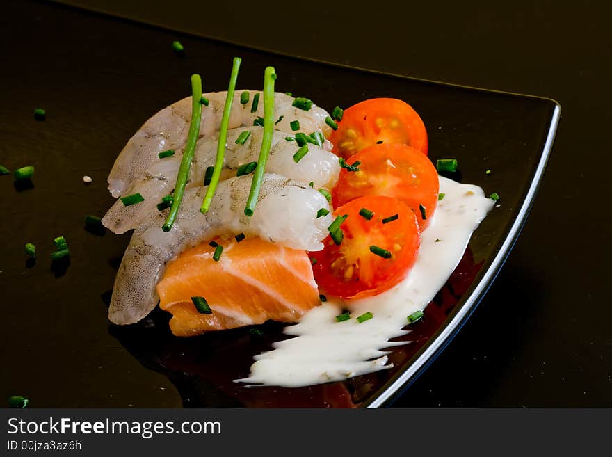 Fresh salmon slice on white platter with salad and prawns served with yogurt cream