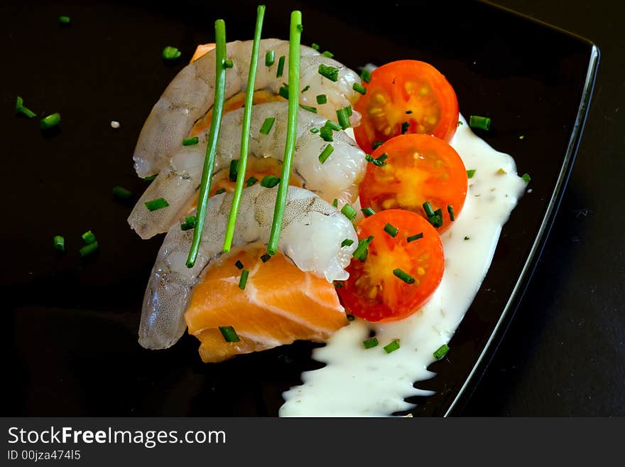 Fresh salmon slice on white platter with salad and prawns served with yogurt cream