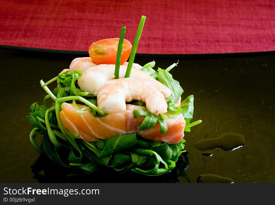 Fresh salmon tartar on black platter with rocket salad