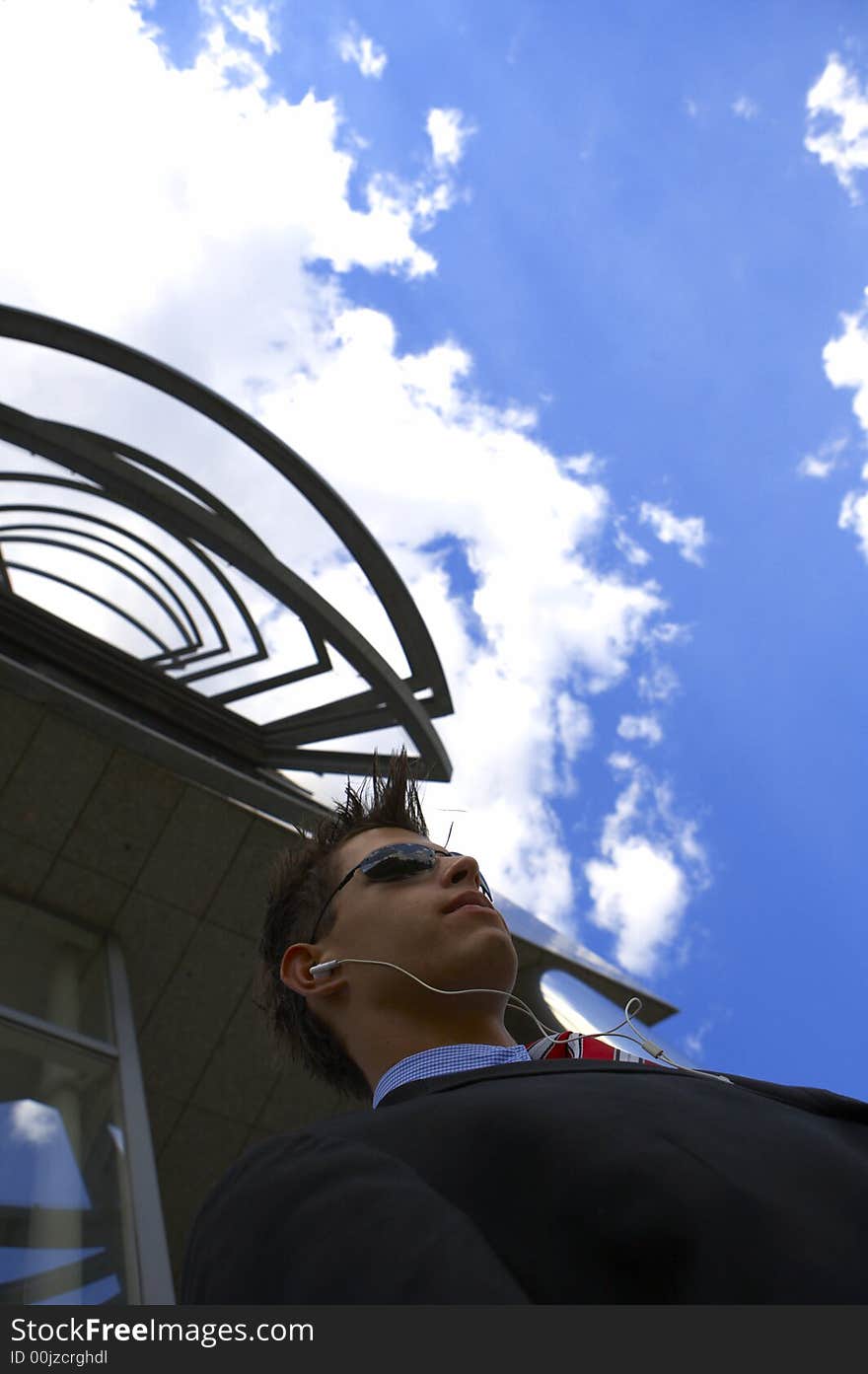 A young business man is listening to his musik while talking a break outside his office. A young business man is listening to his musik while talking a break outside his office