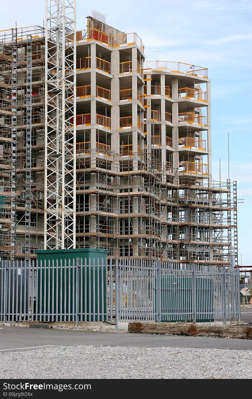 New tall building under construction with scaffolding, against a pale blue sky. New tall building under construction with scaffolding, against a pale blue sky.