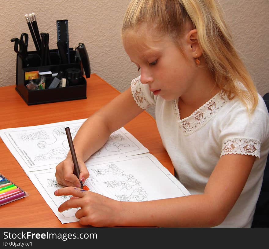 Girl sits at a table and draws