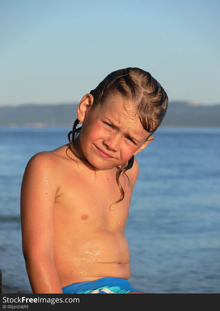 Little child sitting on the stone on the beach in summer. Little child sitting on the stone on the beach in summer