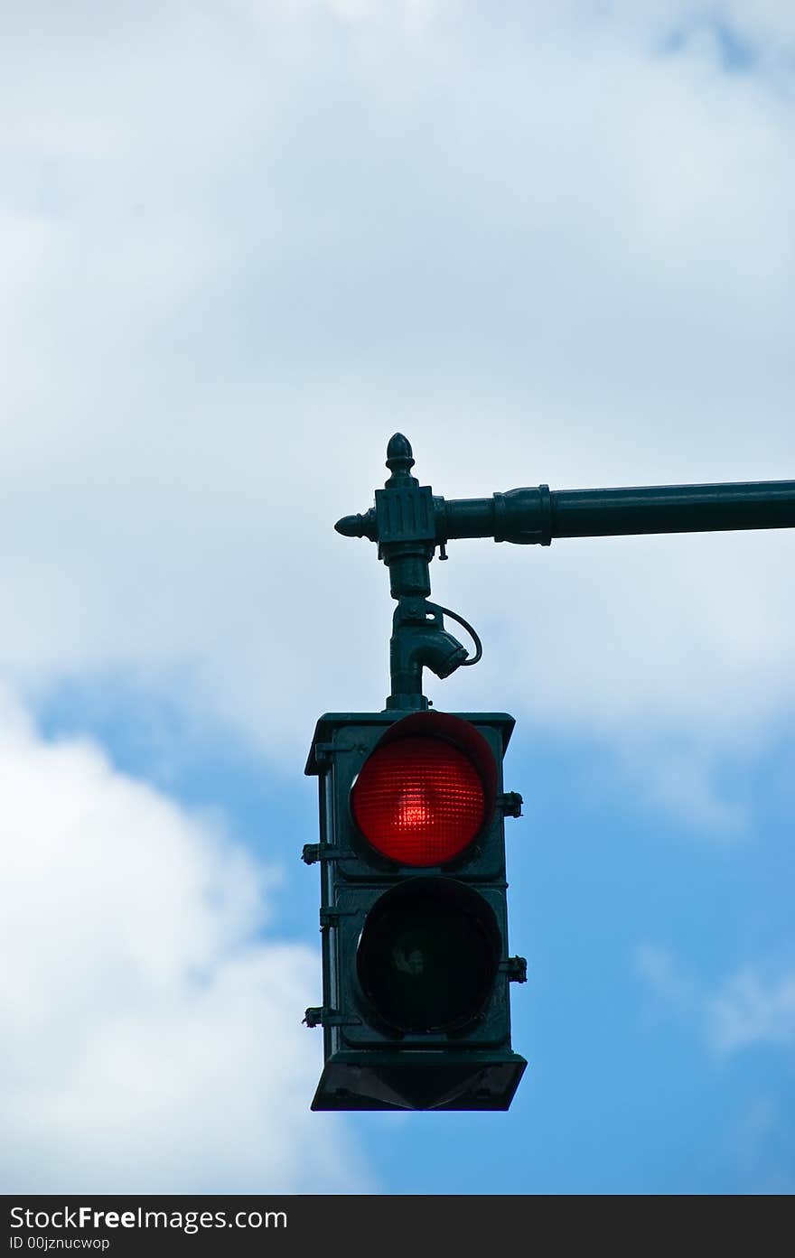 A red stop light overhead against a cloudy blue sky. A red stop light overhead against a cloudy blue sky