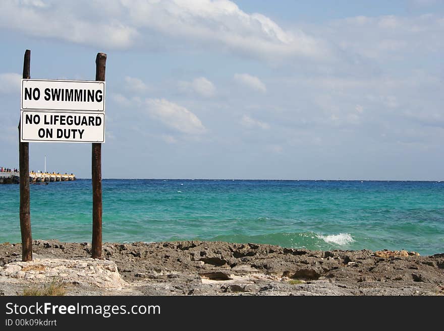 No swimming sign at a rocky beach