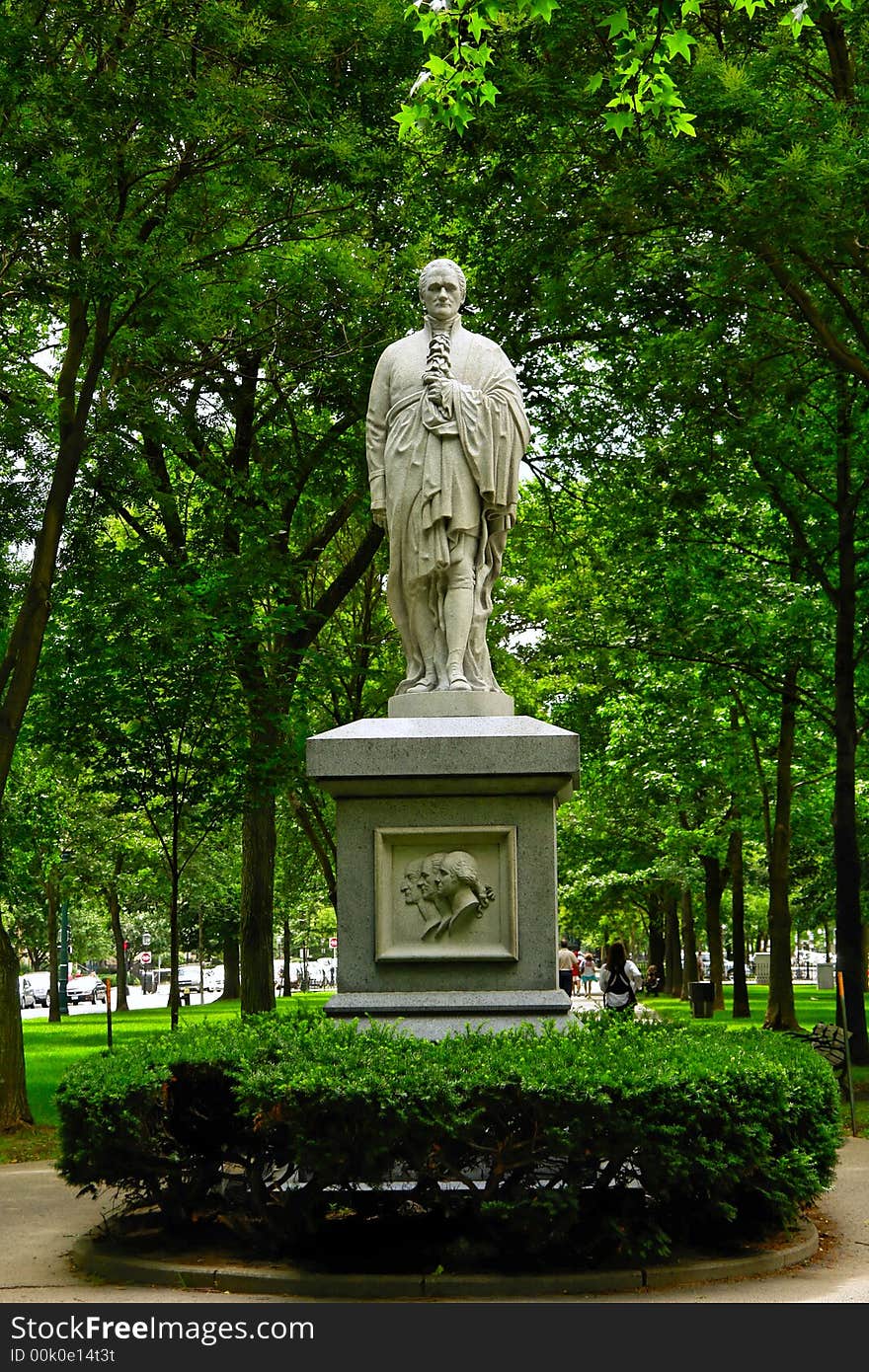 Statue of learned looking man wrapping his claok around him in the middle of a park surrounded by green. Statue of learned looking man wrapping his claok around him in the middle of a park surrounded by green