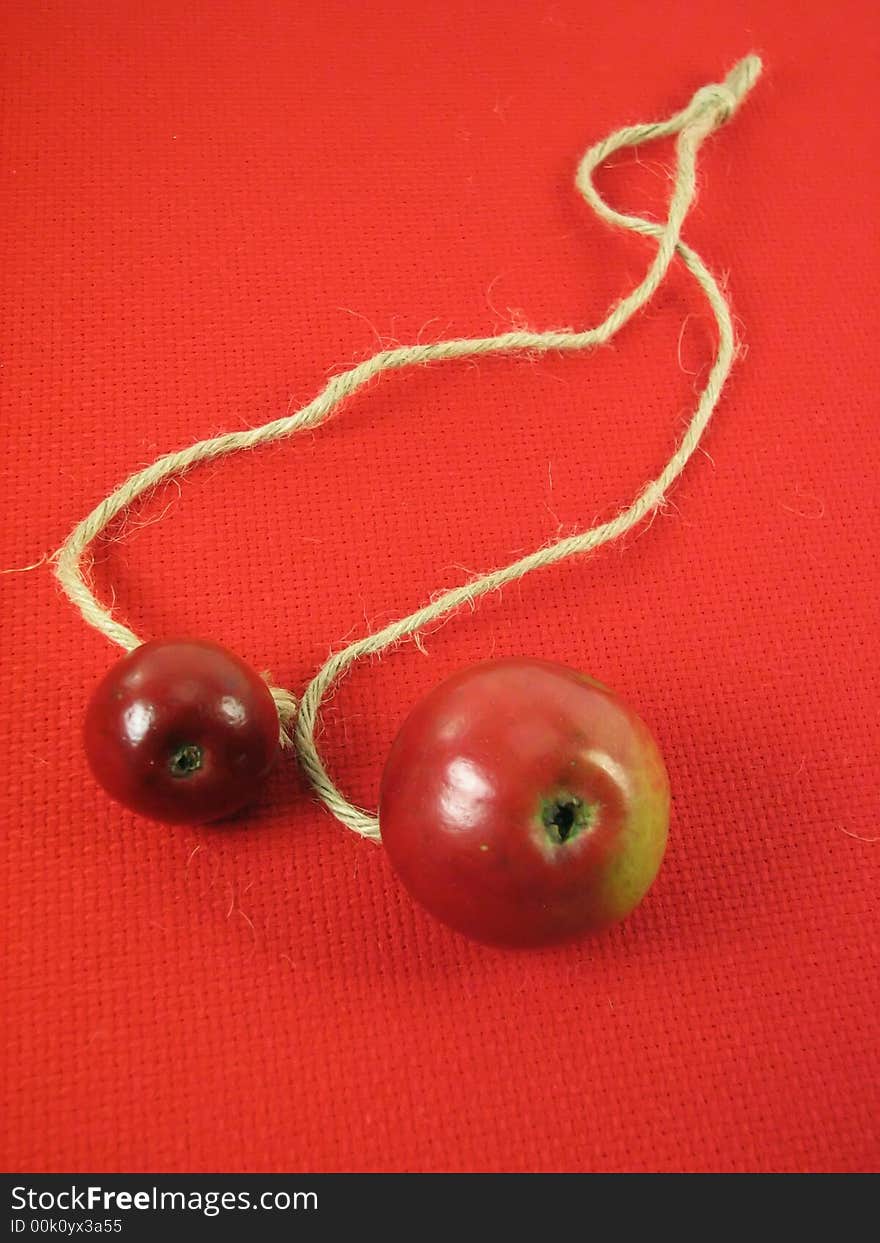 Abstract, composition: red apples and string on red tissue