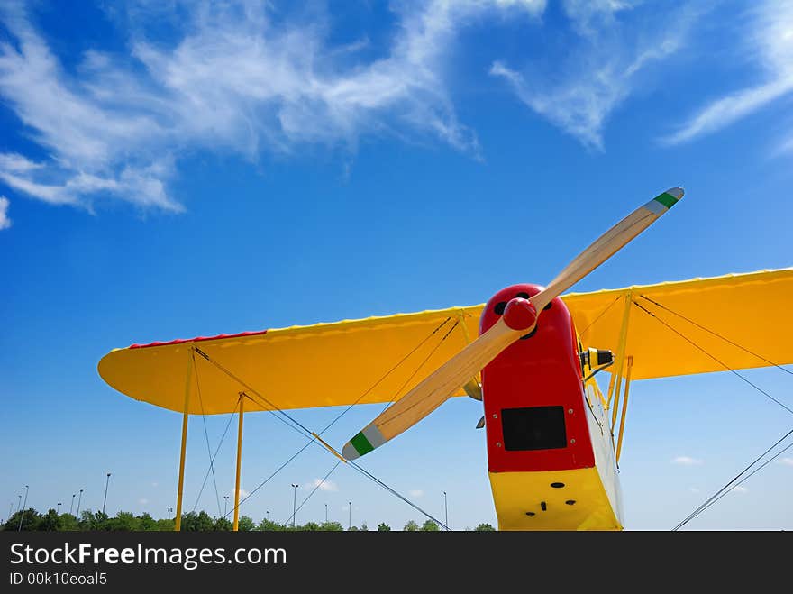 Propeller biplane from below against blue sky