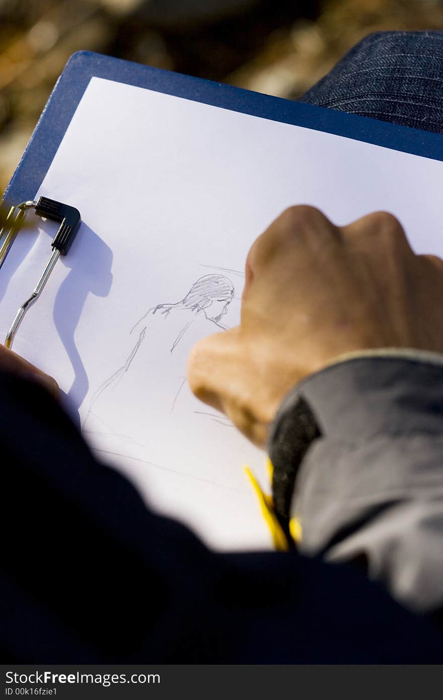 Man sitting and drawing picture in nature with pencil