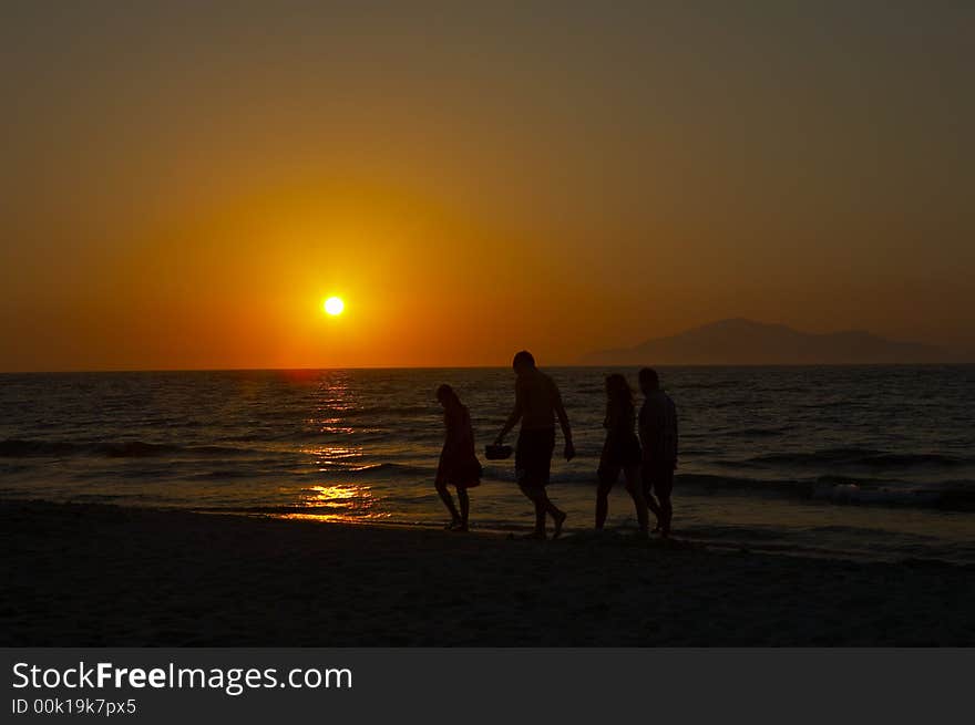 People walking on the beach at sunset. People walking on the beach at sunset