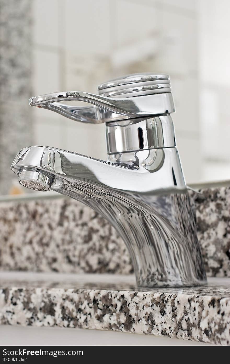 A stainless steel bathroom faucet with foaming nozzle on peppered marble. A stainless steel bathroom faucet with foaming nozzle on peppered marble