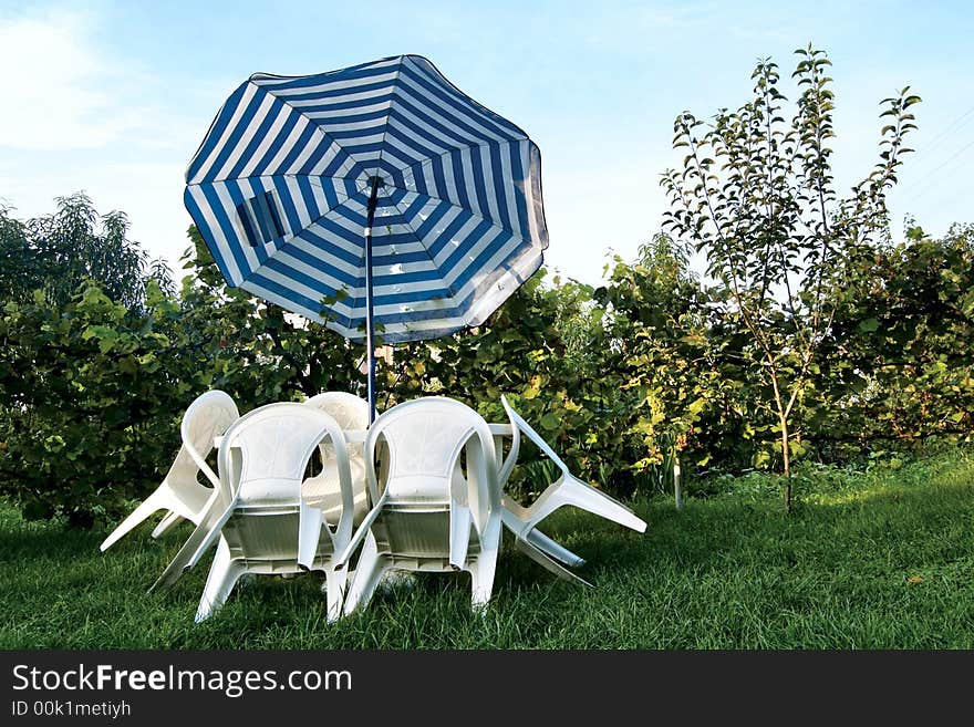 White table and chairs in a garden. White table and chairs in a garden