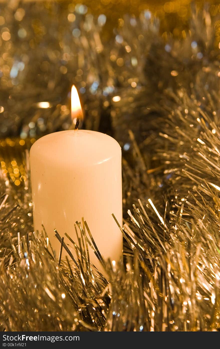 Burning candle in silver and golden tinsel