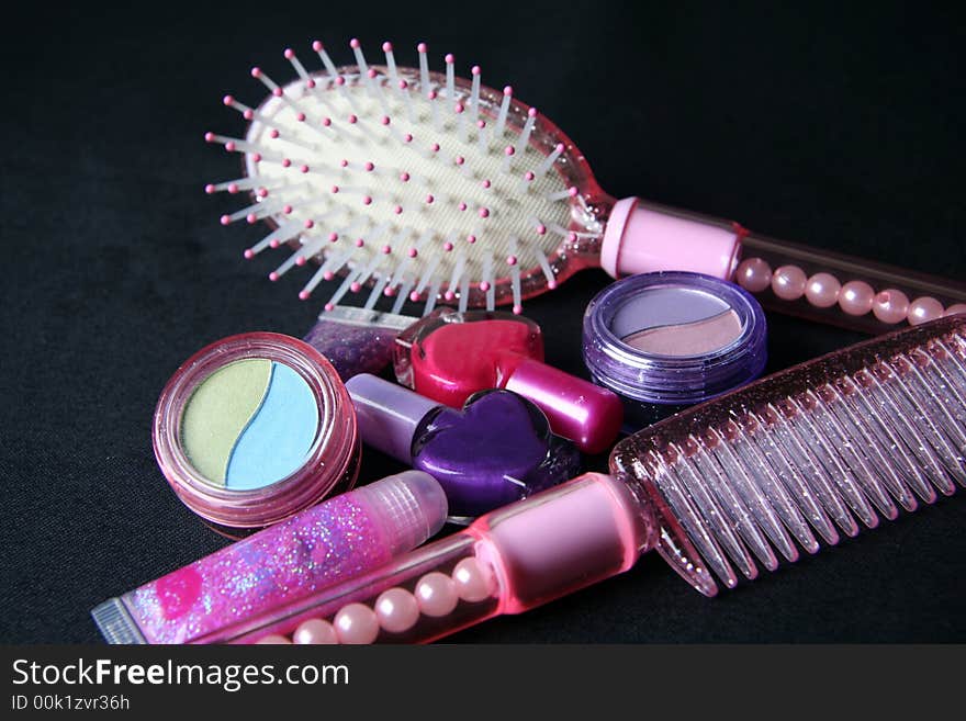 Cosmetics , comb and hair brush over black background