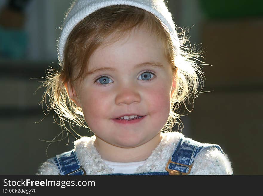 Smiley little girl in white hat over defocused background